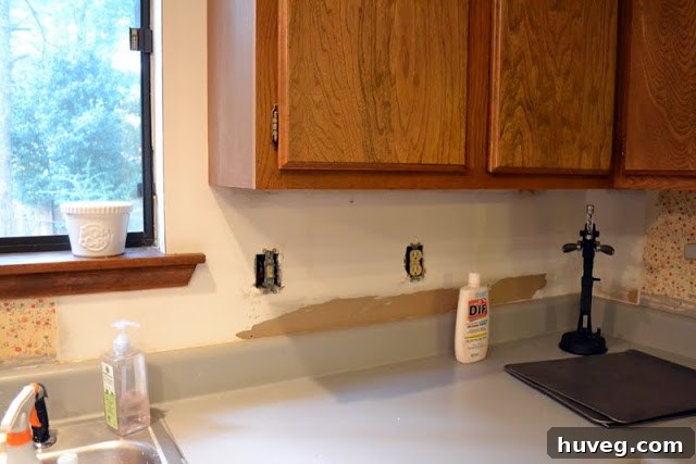 Kitchen wall cleared of wallpaper, ready for backsplash