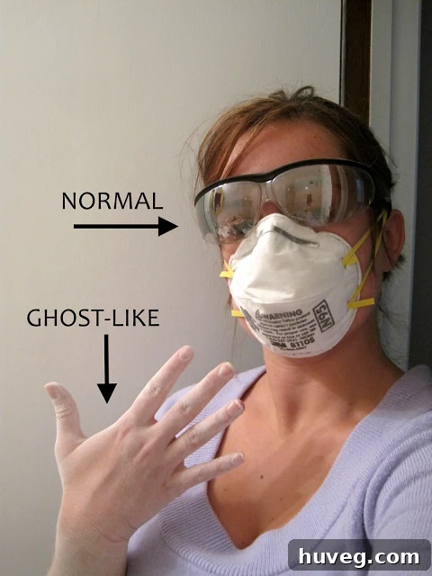 A woman in safety glasses and a respirator mask sanding drywall, highlighting safety in solo DIY.