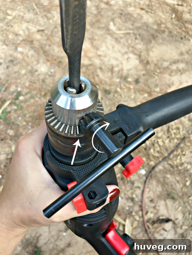 Using a chuck key to rotate and loosen a drill bit