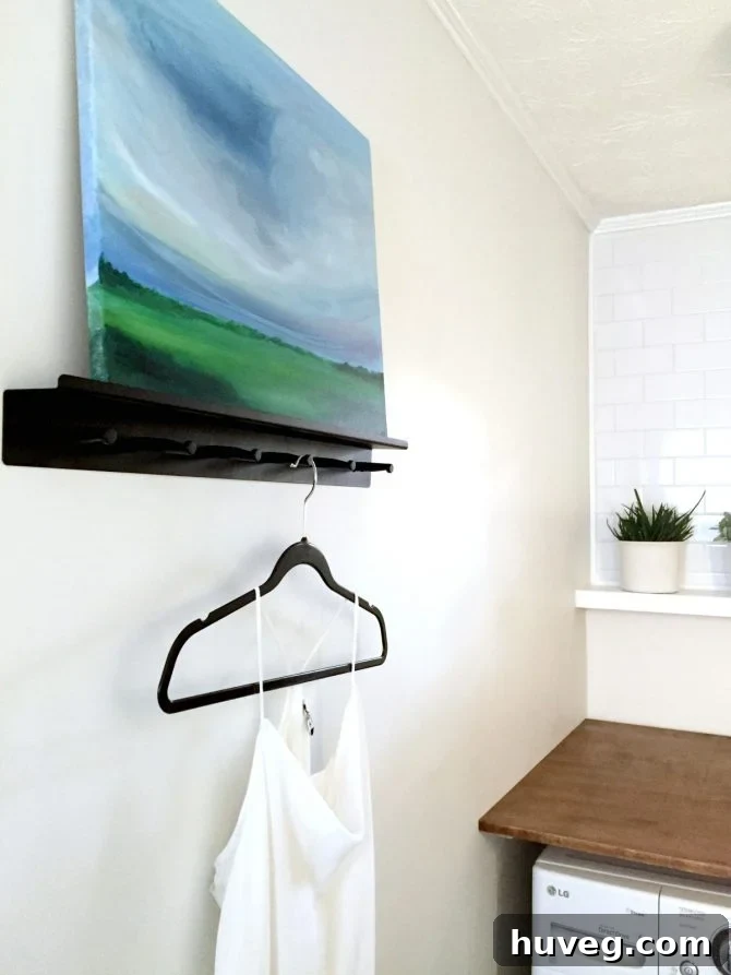 Finished left side of a modern laundry room with custom wall art, white shelving, and a clean aesthetic