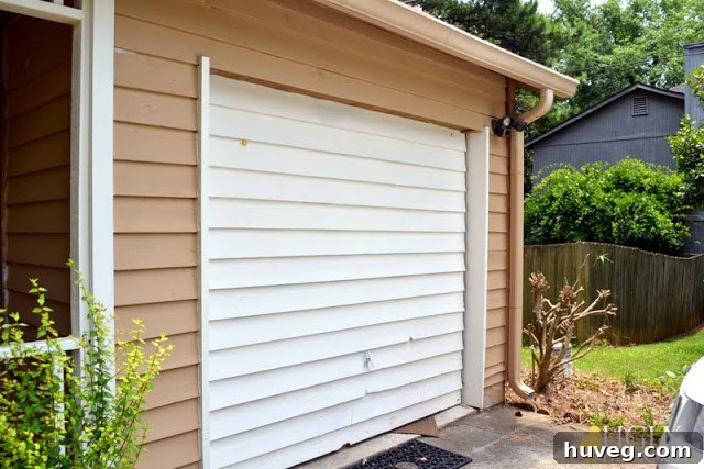 Front view of a white garage door with a visible hole needing repair