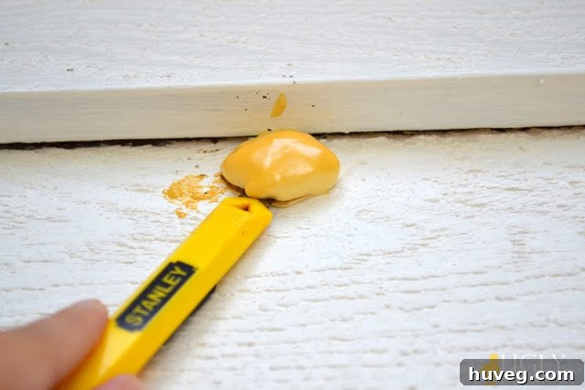 Trimming excess foam sealant from the filled garage door hole for a smooth finish