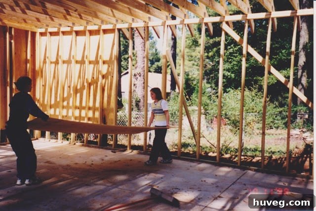 The same two girls and their dad continuing to work on the garage construction, showing progress and the ongoing family collaboration.