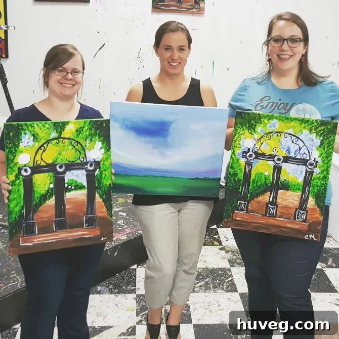 Group picture of friends proudly displaying their finished paintings from a Girls Night Out art class