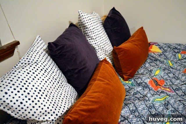 Stylishly made guest bed with various pillows and a duvet cover