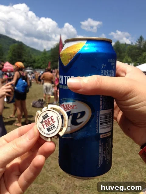A Warrior Dash participant holding a can of beer as a post-race reward, covered in mud.