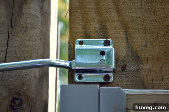 An empty space on the wooden gate where the old latch was removed, showing screw holes and weathered wood