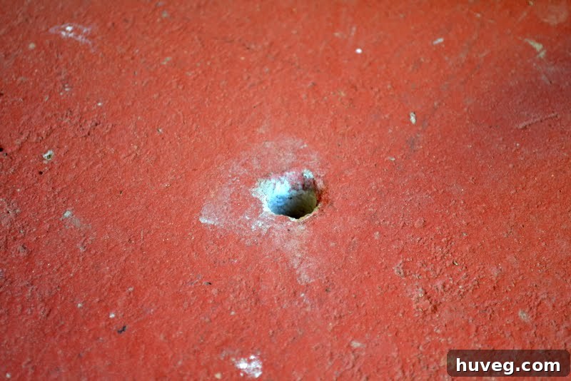 The hole in the concrete slab with a finger for scale