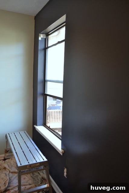 Navy blue wall partially painted, showing the need for a second coat