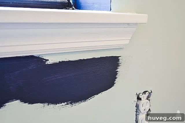 Painter creating a paint reservoir on the wall before cutting in around a window frame