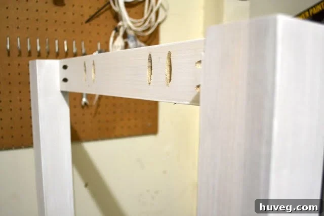 Wide shot of the first DIY desk frame standing completed in the garage, awaiting further assembly.