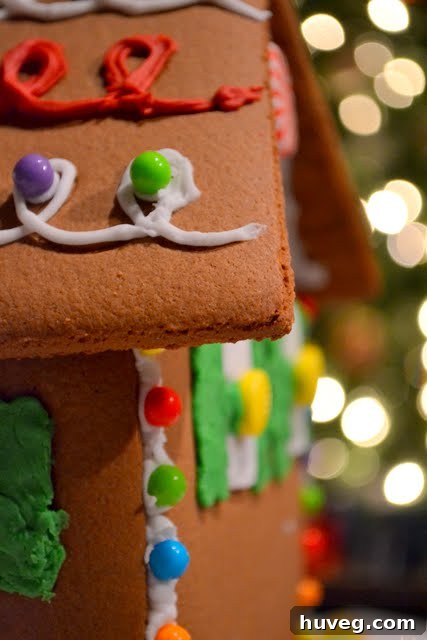 Decorating the gingerbread house roof with white icing and candies