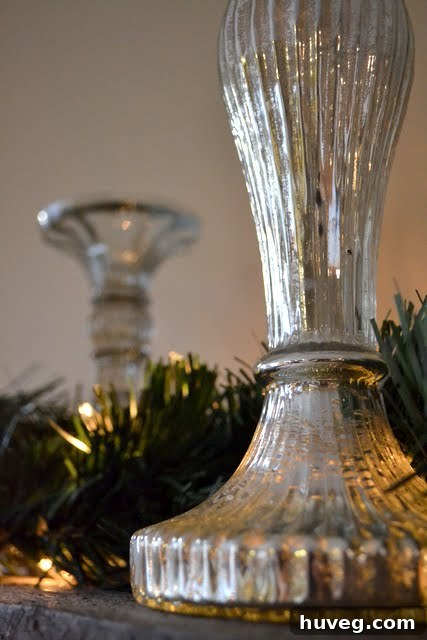 A partially decorated Christmas mantel with garland and candles.
