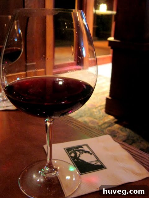 A glass of exquisite red wine served on a scenic patio with a lush green backdrop at The Lodge at Torrey Pines