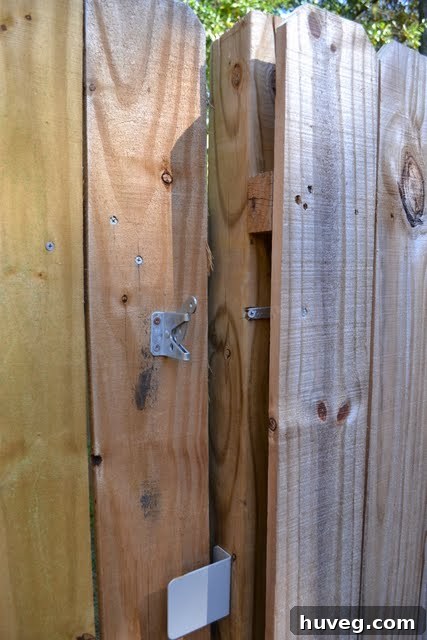 A close-up of a wooden fence with a broken gate latch, showcasing a DIY repair opportunity.