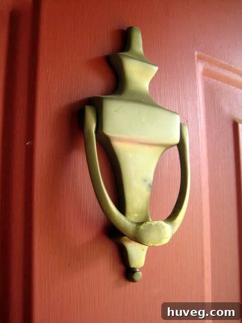 Old, weathered door knocker before painting, showing significant signs of age and wear on the front door