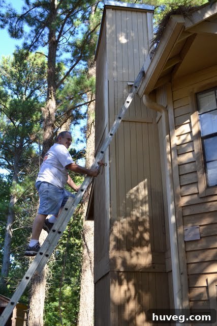 Professional paint sprayer in action, applying the first coat of paint to the house