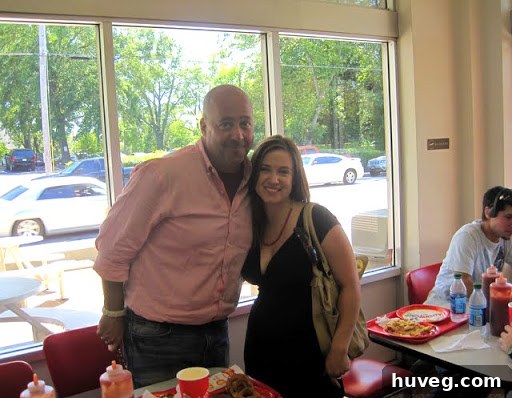 The author making an apologetic face while requesting a photo with Andrew Zimmern, who is eating.