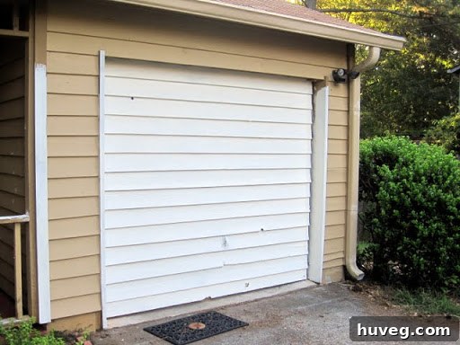 Newly painted garage with warm gingerbread-y house color and creamy white trim, showing initial progress of home exterior update.