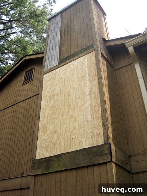 The exterior wall after repairs, showing new siding patches and fresh wood trim, ready for painting and demonstrating significant progress in the renovation.