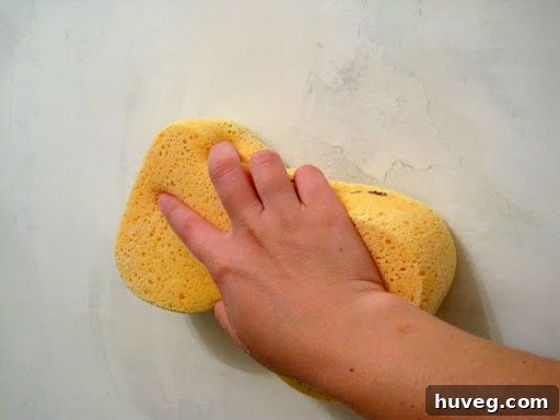 A tile and grout sponge, unexpectedly used for smoothing joint compound on walls.