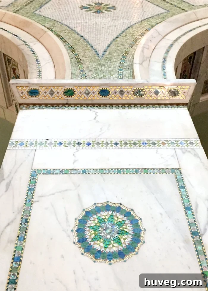 Close-up of exquisite tile and glass inlay details set into marble, showcasing intricate craftsmanship and delicate patterns.