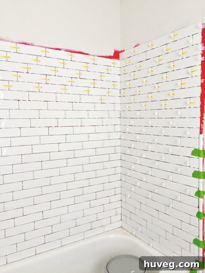 Tiling master bathroom tub surround with elegant long white subway tile, a key step in the renovation