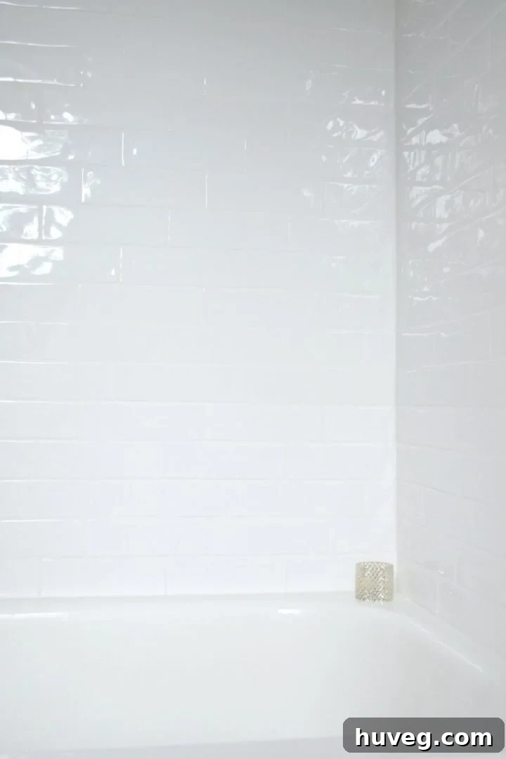 White reflections playing across the handcrafted white tile in the renovated shower, emphasizing texture and light