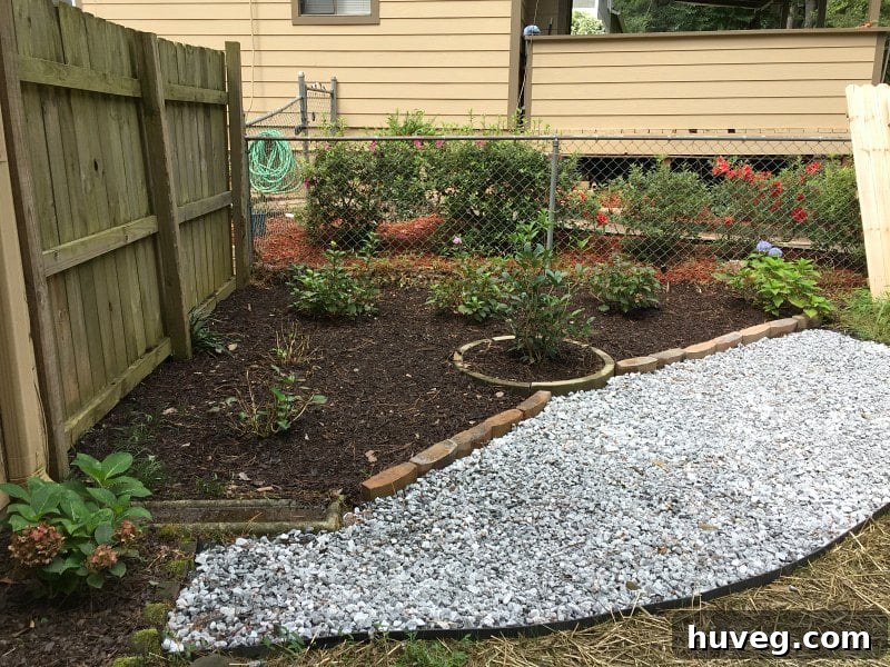 Side angle view of the hydrangea corner garden with partially dried gravel and new stonework. The gravel's color appears more muted and blended, providing a natural aesthetic to the garden.