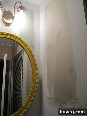 Close-up of bathroom wall post-wallpaper removal, highlighting minor damage and exposed drywall