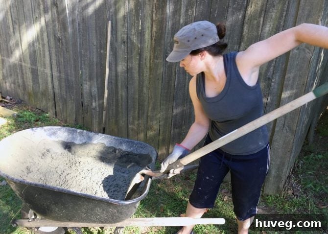 Person mixing cement in a wheelbarrow for a new concrete slab
