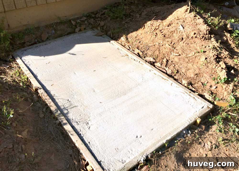 Freshly poured concrete slab for trash bins on the side of the house