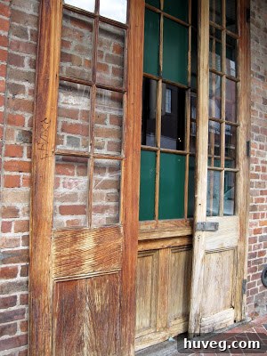Aged green wooden planks with visible grain and faded color, capturing the rustic charm and historic character often found in New Orleans architecture.