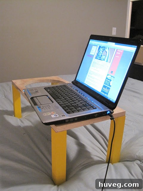Dog dish stand repurposed as a laptop stand on a bed, showing a laptop comfortably placed.