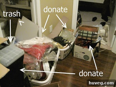 A substantial pile of various household items, including old craft supplies, books, and miscellaneous objects, neatly stacked in the hallway, designated for donation or disposal.