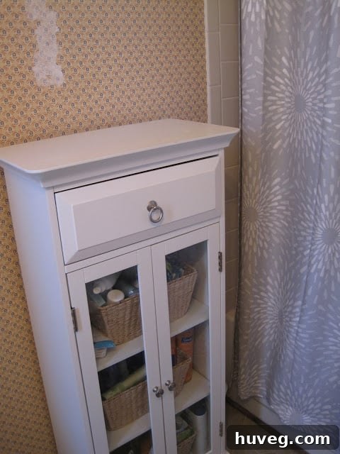 Small, inherited medicine cabinet in the bathroom, showing signs of wear and tear, including rings from tealights on top.