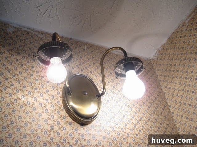Dated light fixture and the hideous wallpaper in the primary bathroom, awaiting replacement.