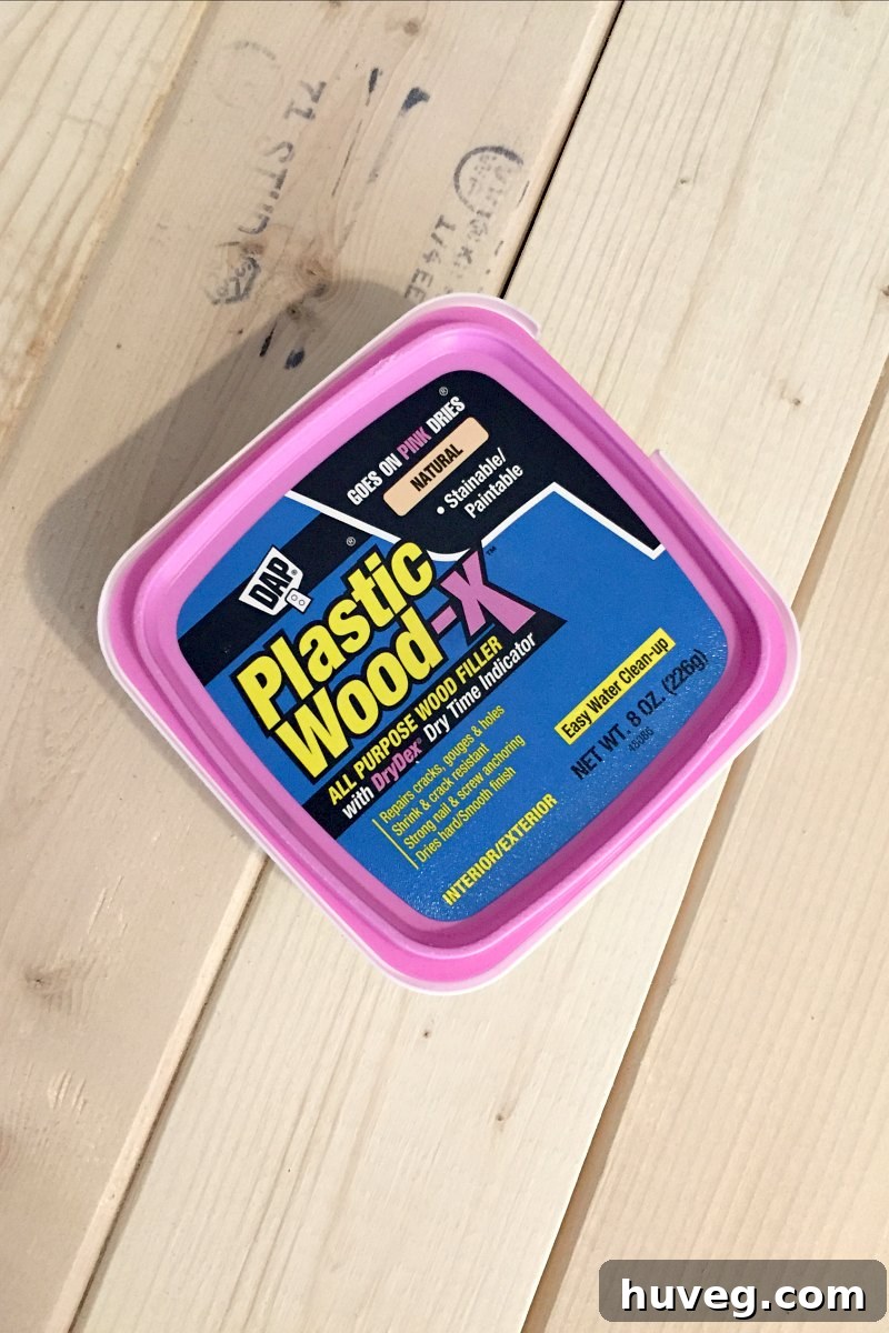 DAP Plastic Wood filler applied to the coffee table, showing its initial pink color before drying.