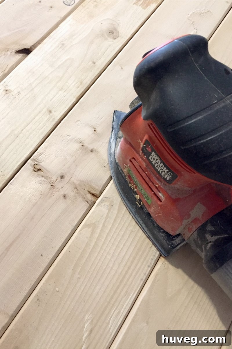 Sanding the coffee table with an orbital sander to achieve a smooth finish.