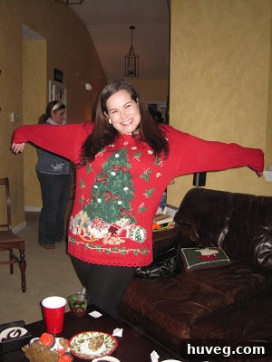 A fellow party-goer showcasing an elaborate and highly decorated tacky Christmas sweater, featuring various holiday motifs and embellishments.