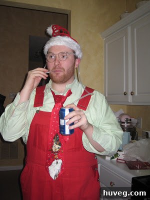 The party host wearing a comically large and intentionally ridiculous sweater, likely a gag gift from a White Elephant exchange, adding to the festive humor.