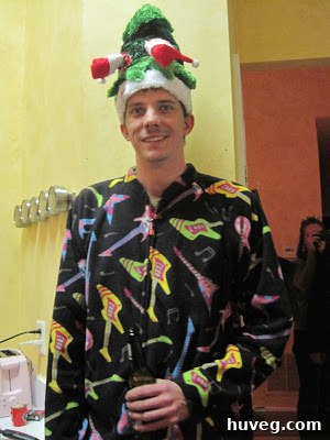 The proud winner of the tacky Christmas sweater contest, wearing an exceptionally elaborate and dazzlingly ugly sweater, holding their prize.