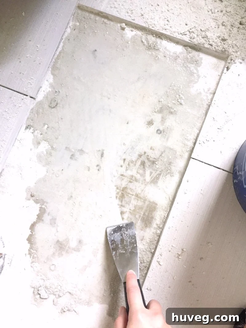 Scraping wet tile adhesive from removed tile area