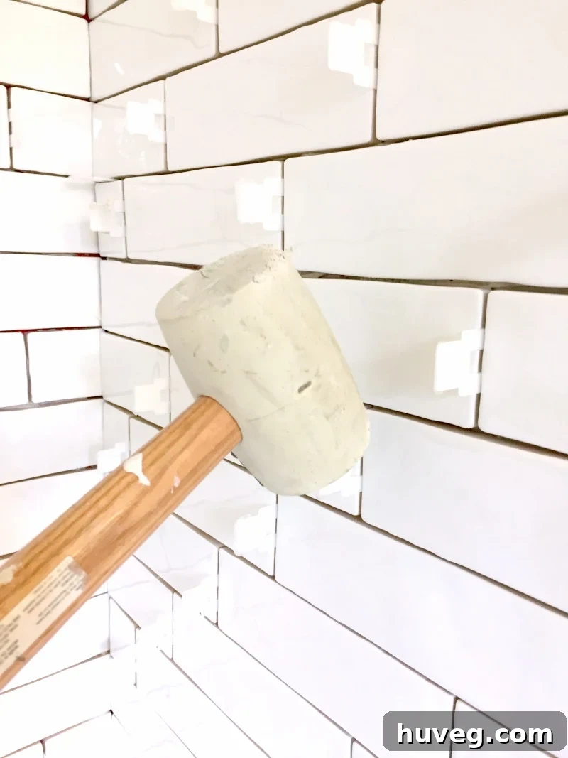 Removing tile leveling spacers with a rubber mallet after tile adhesive has dried