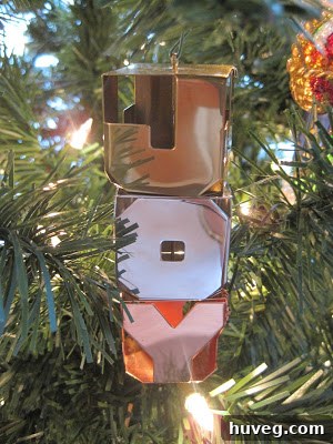 A collection of vintage and modern Hallmark Christmas ornaments, including a prominent 'JOY' ornament, displayed on a decorated Christmas tree with various other festive decorations.