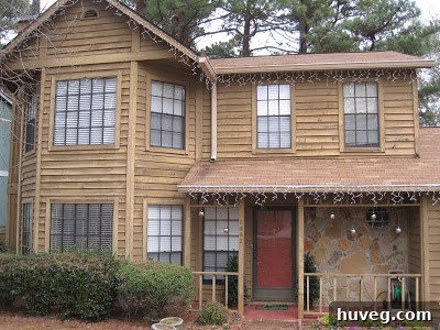 The large lit Christmas wreath securely hung on the second-story window, perfectly completing the home's outdoor holiday decor.