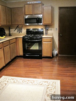 After photo of the renovated kitchen, showcasing new dark wood flooring and sleek, modern appliances.