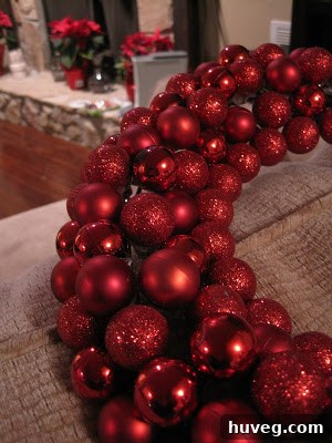 Close-up of partially assembled red ornament wreath, showing texture and varying ornament sizes