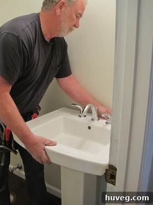 Close-up of the pedestal sink being reinforced to the wall.