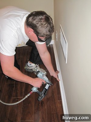 Scott skillfully operating an air nailer to install elegant shoe molding along the base of the wall, showcasing the ease and speed of modern trim installation.